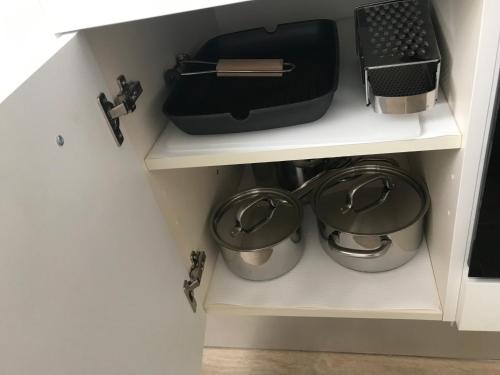 a kitchen cabinet with pots and pans on a shelf at Chioggia House di Davide in Chioggia