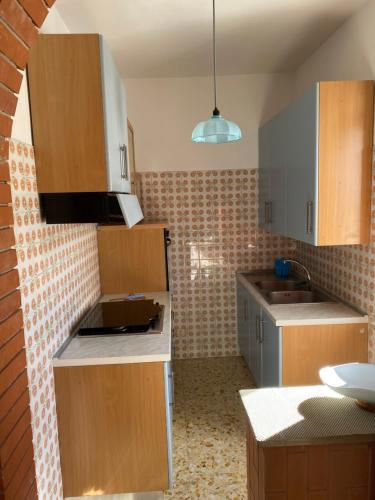 eine kleine Küche mit Holzschränken und einem Waschbecken in der Unterkunft VILLA PINETA VISTA MARE in San Menaio
