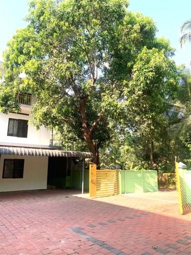 a tree in front of a building with a yellow gate at Airavatham Apartments in Guruvāyūr