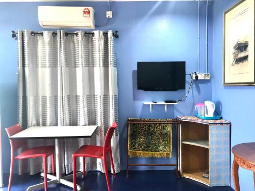 um quarto azul com uma mesa e cadeiras e uma televisão em WAN'S ROOMSTAY LANGKAWI em Pantai Cenang