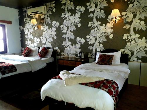 Habitación de hotel con 2 camas y papel pintado con motivos florales en Wild Adventure Resort, en Sauraha