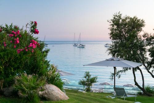 a beach with an umbrella and a boat in the water at Hotel Stella Maris in Villasimius