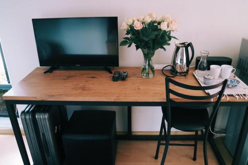 a desk with a television and a vase of flowers at 9 Windsor House in Tokai
