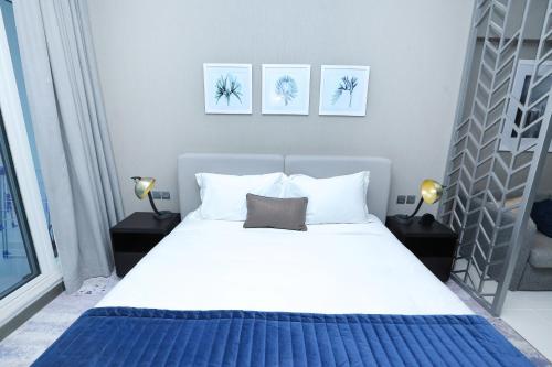 um quarto com uma grande cama branca e 2 candeeiros em DAMAC MAISON PRIVE em Dubai
