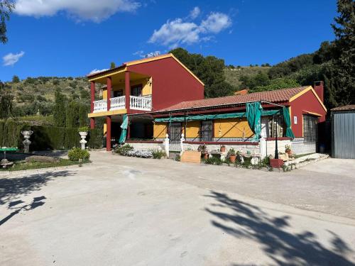 a large red house with a balcony on a driveway at Vivienda Rural Villa Ruben in Jaén