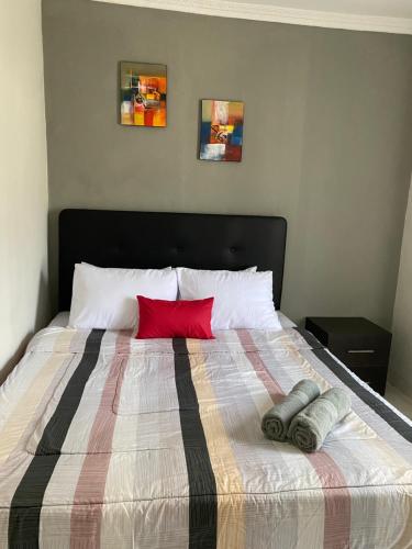 a bed with a red pillow and two pillows on it at AW Simply House Yogyakarta in Ngabean