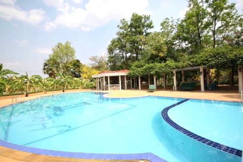 a large blue swimming pool with trees in the background at Hermitage Hotel Korat-SHA in Nakhon Ratchasima