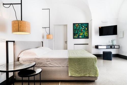 a bedroom with a bed and a table and a tv at Palazzo De Noha - Boutique Hotel in Lecce