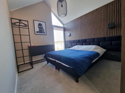 a bedroom with a blue bed and a window at BOSKO domki z sauną i balią w Sulminie obok Gdańska in Sulmin