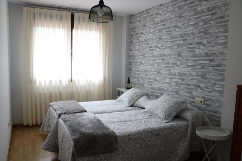 ein Schlafzimmer mit einem Bett und einer Ziegelwand in der Unterkunft La Tilar, apartamento con gran terraza a 3 km de la playa in Llanes