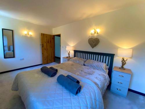 a bedroom with a large bed with blue pillows on it at Trelaske Mill Cider Barn-with Hot Tub, Fire Pit BBQ in Lewannick