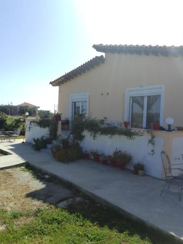 una casa blanca con un patio delante en Studios ΣΤΟΥΣ ΠΥΡΓΟΥΣ ΘΕΡΜΗΣ en Mitilene