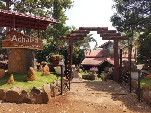 an entrance to a garden with a sign and rocks at Achalaa Resort in Kolhapur