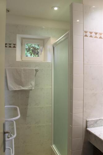 une douche avec une porte vitrée dans une salle de bain dans l'établissement Bastidon avec piscine Gordes Lubéron, à Gordes