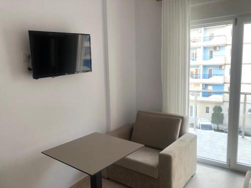 a living room with a couch and a table and a television at Hotel MARIO, Shengjin in Shëngjin