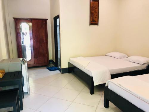 a room with two beds and a desk and a window at Hoang Nga Garden Guesthouse in Mui Ne