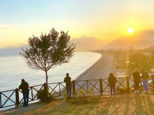 a group of people standing around a fence watching the sunset at Casa Franco in Antalya