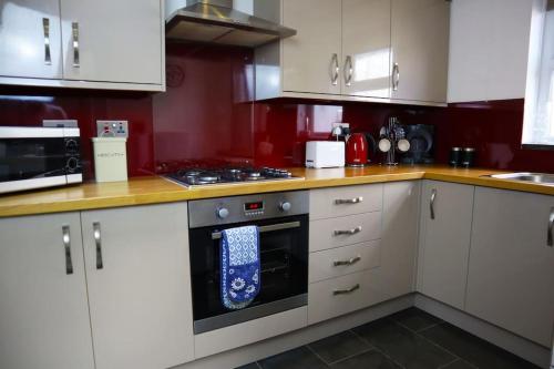 a kitchen with white cabinets and a stove top oven at Dol Bach - Your homely Welsh Cottage in the Heart of Snowdonia in Blaenau-Ffestiniog
