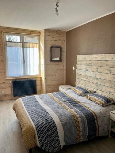 une chambre avec un grand lit avec une tête de lit en bois dans l'établissement Appart Chez NONO, à Patornay