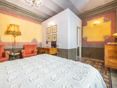 a bedroom with a large white bed and two chairs at PALAZZO CHERCHI in Dorgali