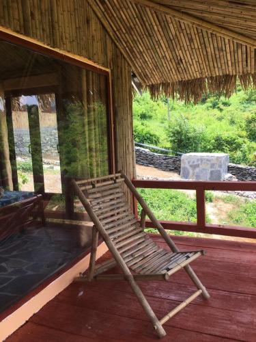 a wooden rocking chair on a porch of a house at Mộc Châu Peachy Garden in An Pon