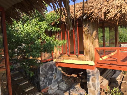 a house with a porch and a stone fireplace at Mộc Châu Peachy Garden in An Pon