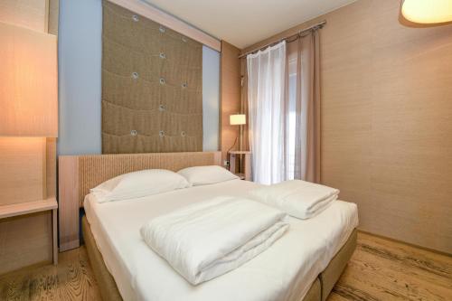 a bedroom with a large bed with white sheets at Hotel Flaminia in Sirmione