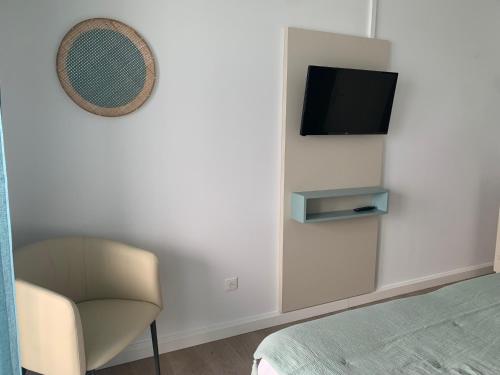 a bedroom with a chair and a tv on a wall at Hotel Beau Rivage in Algajola