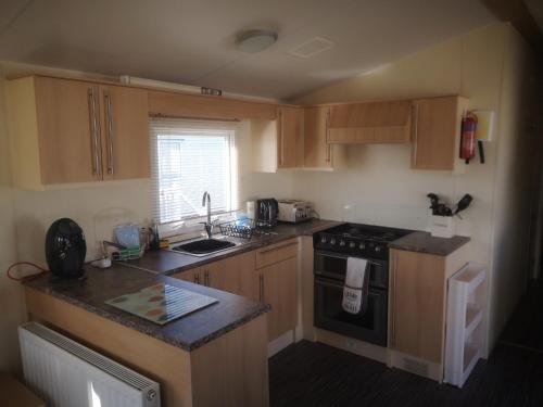 a kitchen with wooden cabinets and a stove top oven at Caravan L25 in Mablethorpe