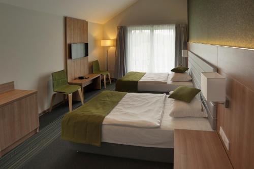 a hotel room with two beds and a tv at Kalinowe Pola Golf Village in Niesulice