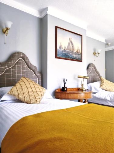 two beds in a hotel room with a yellow blanket at Villa Rothsay Hotel in Cowes