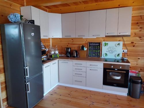 eine Küche mit weißen Schränken und einem schwarzen Kühlschrank in der Unterkunft House ThoNi in Gornji Štoj