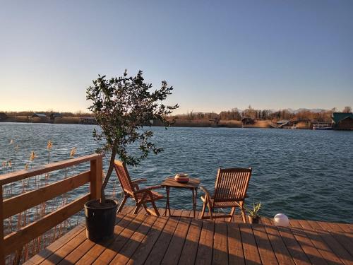 two chairs and a table on a dock next to a lake at House ThoNi in Gornji Štoj