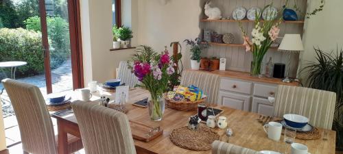 a dining room table with vases of flowers on it at Cowpasture Barn B&B in Eye