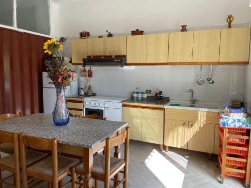 a kitchen with a table with a vase of flowers on it at La casa di Mussiù in Salemi