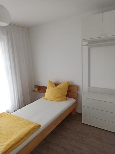 a bedroom with a bed with a yellow pillow on it at Ferienwohnung Michelfeld in Michelfeld