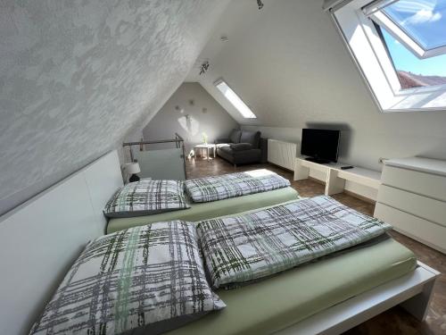 um quarto no sótão com 2 camas e uma televisão em Ferienhaus Zum Gässchen em Weißenfels
