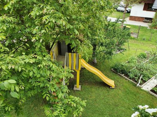 a yellow slide in a yard next to a tree at Sobe Ćuskić in Bohinj