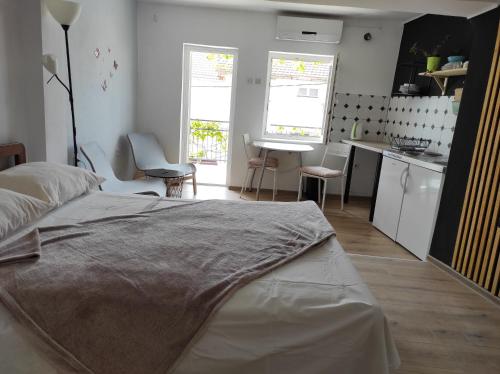 a bedroom with a large bed and a kitchen at Apartment Seventh Continent in Šibenik
