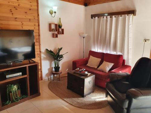 Una sala de estar con un sofá rojo y un televisor de pantalla plana. en Sharvit Hakesem, en Livnim