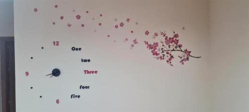 a clock with pink flowers on a white wall at Giusy's Place 2.0 in Campofelice di Roccella