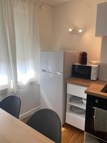 W kuchni znajduje się biała lodówka i kuchenka mikrofalowa. w obiekcie 2nd floor Cozy Central Flat with free parking w mieście Boulogne-sur-Mer