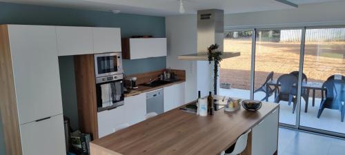 cocina con armarios blancos y encimera de madera en Chambre indépendante avec terrasse, en Romille