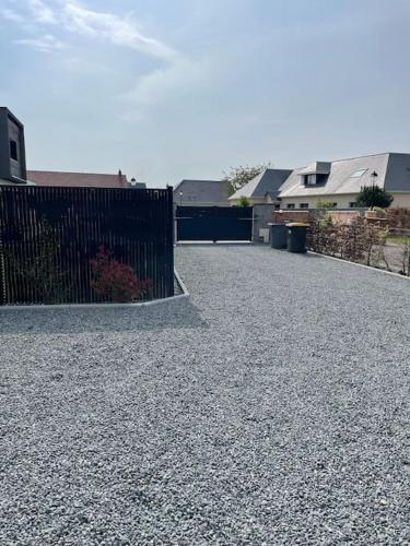 uma entrada de cascalho com uma cerca preta e casas em Maison chaleureuse au calme em Roumare