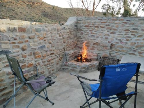 two chairs and a fire pit in a stone wall at Jacomanzi in Plathuis