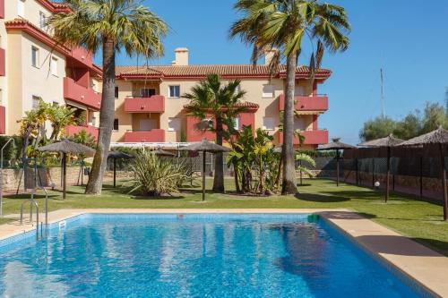 a swimming pool in front of a building with palm trees at MyChoice Los Corrales by Bossh! Apartments in Rota