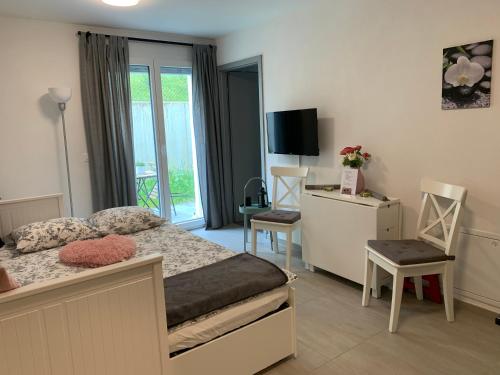 1 Schlafzimmer mit einem Bett und 2 Stühlen sowie einem TV in der Unterkunft Studio Doux rayon in Lausanne