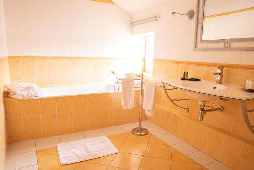 La salle de bains est pourvue d'une baignoire et d'un lavabo. dans l'établissement Hôtel Bellevue, à Puy-lʼÉvêque