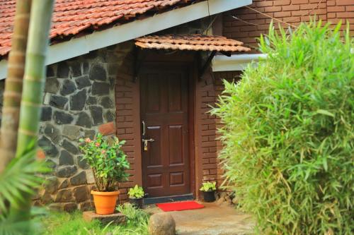a wooden door of a house with potted plants at Achalaa Resort in Kolhapur