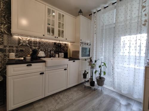 a kitchen with white cabinets and a sink and a window at Sweet home R&M in Split